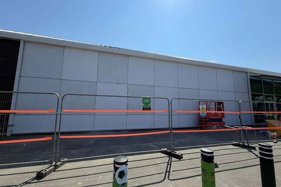 Completed white-rendered external elevation of an Asda store in Bristol behind site barriers