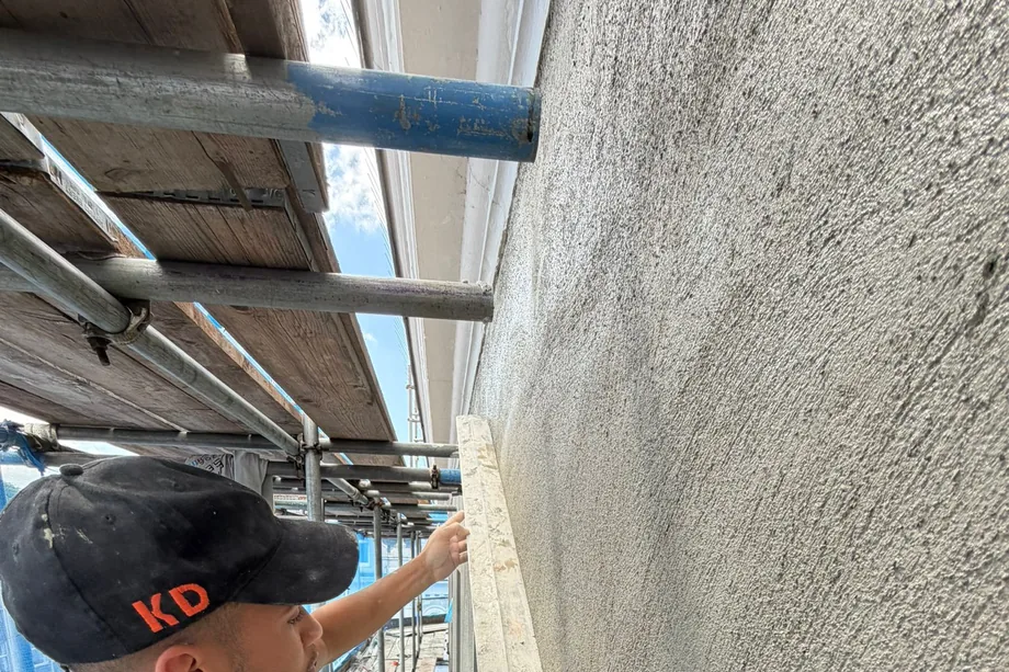 KD Plastering plasterer ruling off a fresh float coat with a feather-edge on the HSBC bank building in Bristol