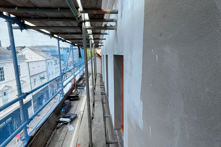Scaffolded elevation of the HSBC bank building in Bristol with a freshly floated render coat, rooftops beyond