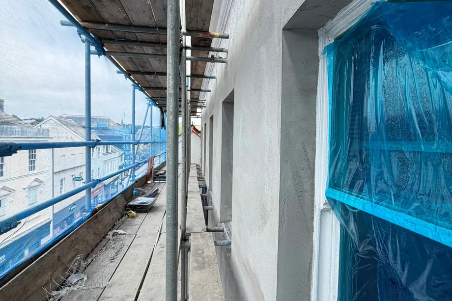 Freshly rendered wall on the HSBC bank building in Bristol with a sharp formed reveal around a masked sash window