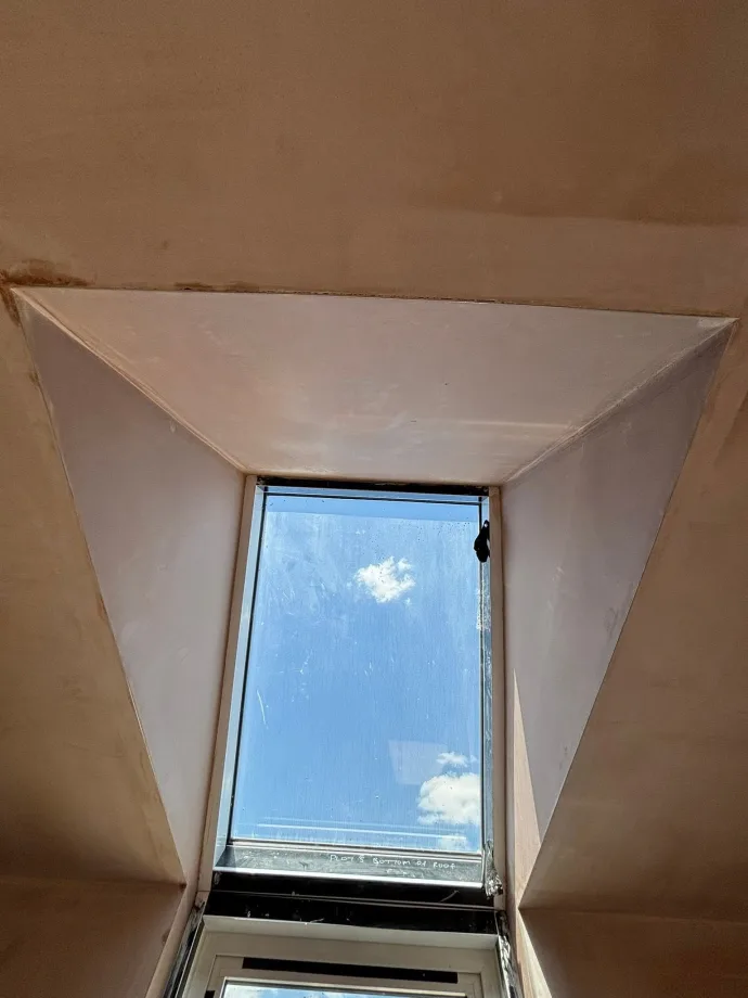 Splayed Velux reveal, freshly skimmed, with sky through the opening