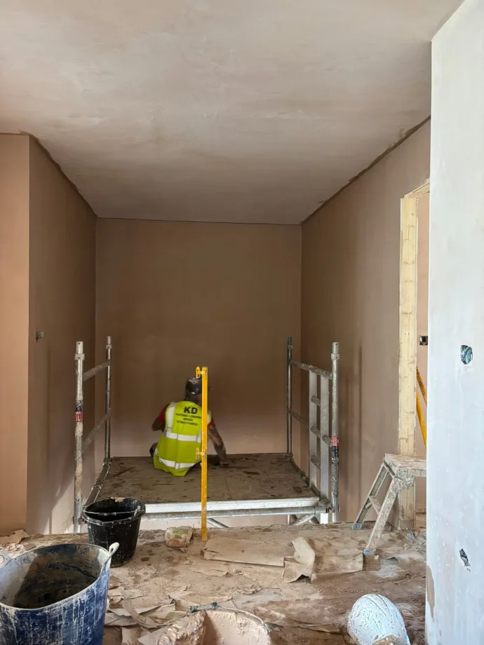 Plasterer on a mobile tower skimming a ceiling